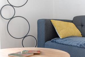 a blue couch with a yellow pillow and a table at Le pied à terre d'ernest in Limoges