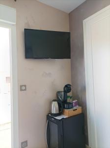 a television hanging on a wall with a microwave at SUITE SPA PRIVATIF 66 Nord de Perpignan in Pia