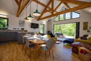 a dining room and living room with a table and chairs at Tresillian Lodge Waterfront, Forest, Hot tub,Sauna in Truro