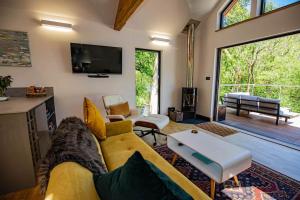 uma sala de estar com um sofá amarelo e uma televisão em Tresillian Lodge Waterfront, Forest, Hot tub,Sauna em Truro
