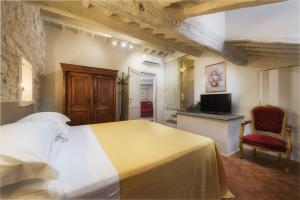 1 dormitorio con 1 cama, TV y silla en Terrazza Silena, centro storico con vista Cortona!, en Cortona
