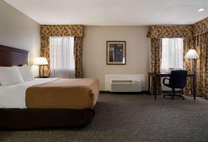 Habitación de hotel con cama y escritorio en Quality Inn, en Grand Blanc