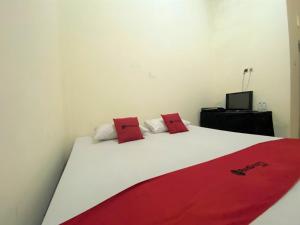 a bed with two red pillows on top of it at RedDoorz near GOR Lagaligo Palopo in Palopo