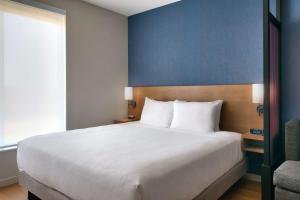 Un dormitorio con una cama blanca y una pared azul. en Hyatt Place Fayetteville/Springdale, en Fayetteville