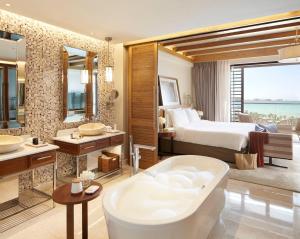 a bathroom with a tub and a bedroom with a bed at Jumeirah Al Naseem Dubai in Dubai