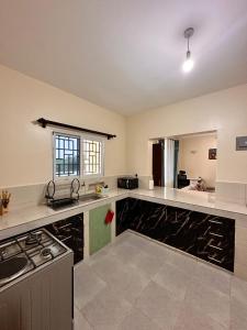 a large kitchen with white counters and a stove at Shawell Homes in Kilifi