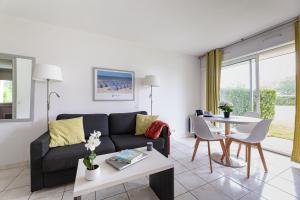 uma sala de estar com um sofá e uma mesa em Résidence Goélia Green Panorama em Cabourg