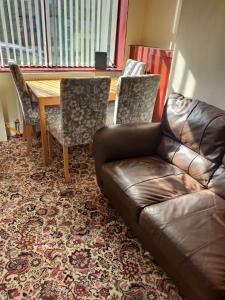 a living room with a leather couch and a table and chairs at Paradise Apartment- Female Only in Bradford