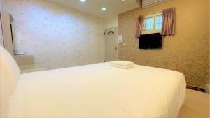 a bedroom with a large white bed with a window at Fengjia Jocy House in Taichung