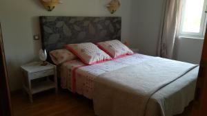 a bedroom with a bed with pink pillows on it at Chambres d'hôtes Chez Dumitra in Calès