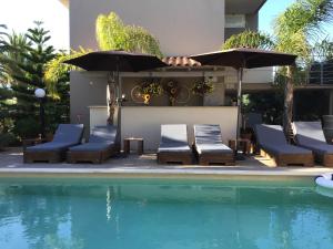 a group of chairs and umbrellas next to a pool at Evie's Houses in Kalathas