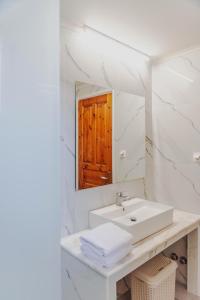 a white bathroom with a sink and a mirror at Four Seasons Vacation House in Lefkímmi +34 photos