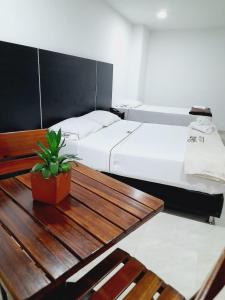 Zimmer mit 2 Betten und einem Holztisch in der Unterkunft Hotel Saint John in Medellín