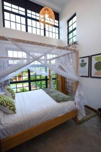 a bedroom with a bed with a canopy and windows at Private Villa at the Source of the Nile in Jinja