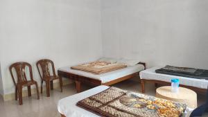 a room with two beds and two chairs and a table at HOTEL PINE RESORT NETALA in Uttarkāshi