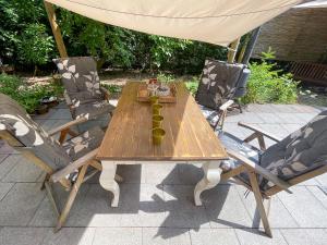 a wooden table with two chairs and a umbrella at Boschalet Magnolia in Voorthuizen
