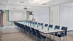 a conference room with a long table and blue chairs at Hey Lou Hotel Friedrichshafen in Friedrichshafen