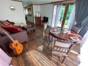 a living room with a couch and a table with a guitar at Boschalet Magnolia in Voorthuizen