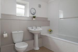 La salle de bains blanche est pourvue de toilettes et d'un lavabo. dans l'établissement Farmyard Cottage, à Malmesbury