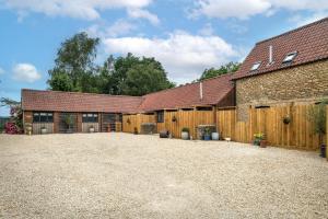 a barn with a gravel driveway in front of it at Farmyard Cottage in Malmesbury