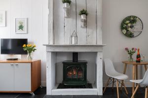 a living room with a fireplace and a tv at Little Calf Cottage in Malmesbury