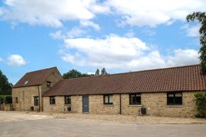 een oud bakstenen gebouw met een bruin dak bij Little Calf Cottage in Malmesbury