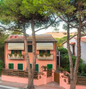 un bâtiment rose avec des volets verts et des arbres dans l'établissement Hotel Elba, à Marina di Campo