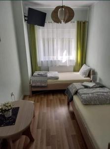 a room with two beds and a table and a window at Noclegi Sławomir Zabłocki Bydgoszcz/Nakło nad Notecią i okolice in Strzelewo