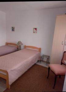 a bedroom with two beds and a chair at Apartman SLADJANA Vrnjacka Banja in Vrnjačka Banja