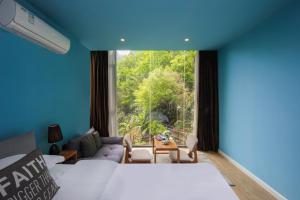 a room with a bed and a large window at Garden Villa Resort Yangshuo in Yangshuo