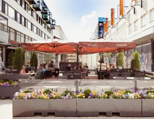 an outdoor cafe with umbrellas and flowers in a city at Hotel Emilia in Hämeenlinna