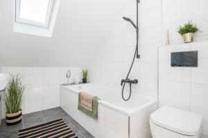 La salle de bains blanche est pourvue d'une baignoire et de toilettes. dans l'établissement Kurzzeitglück 24h Self Check-In MH01, à Mülheim