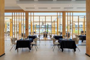 Cleopatra Luxury Resort Sharm - Adults Only 16 years plus في شرم الشيخ: غرفة طعام مع طاولات وكراسي ونوافذ