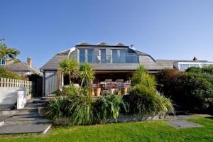 a house with glass windows and plants in a yard at Higher Close in Mawgan Porth