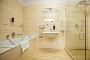 a bathroom with a tub and a sink and a shower at Hotel Litovel in Komárno