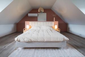 una camera da letto con letto bianco in mansarda di Logies Op 't Gestel a Opglabbeek