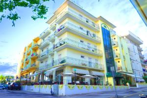 ein hohes gelbes Gebäude mit Sonnenschirmen davor in der Unterkunft Hotel Athena B&B in Gabicce Mare