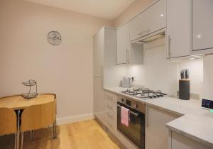 a kitchen with white cabinets and a stove top oven at The Marchmont Residence in Edinburgh