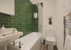 a green tiled bathroom with a toilet and a sink at The Marchmont Residence in Edinburgh