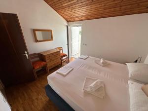 a bedroom with a white bed with towels on it at Guest house Šuda in Lumbarda