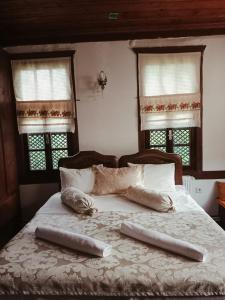 a bed with two pillows on it with two windows at Asya konak in Safranbolu