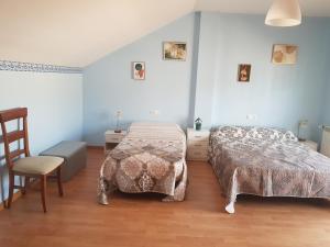 1 dormitorio con 2 camas y 1 silla en Apartamento Alhondiga Hervás, en Hervás