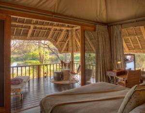 a bedroom with a bed and a balcony at Finch Hattons Luxury Tented Camp in Tsavo