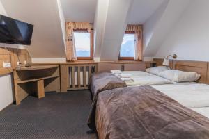 a hotel room with two beds and a flat screen tv at Hotel Krvavec in Cerklje na Gorenjskem