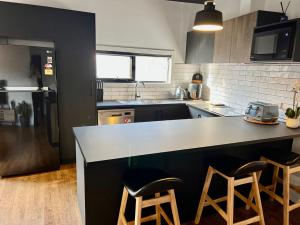 eine Küche mit einer Theke und 2 Hockern in der Unterkunft CBD Elizabeth St Modern Townhouse - Secure Parking in Launceston