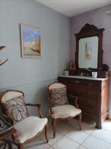 Pokój z 2 krzesłami, komodą i lustrem w obiekcie SUITE SPA PRIVATIF extérieur 66 Perpignan Nord w mieście Pia