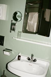 ein Badezimmer mit einem Waschbecken, einem Spiegel und Handtüchern in der Unterkunft Hotel Am Brillantengrund in Wien