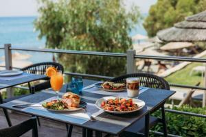 a table with two plates of food and a drink at Atlantica Bay - Adults Only in Limassol