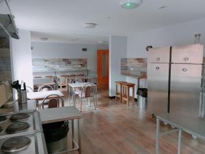 Belfast International Youth Hostel في بلفاست: غرفة مع طاولات وكراسي ومطبخ مع شطافات