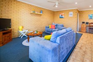 ein Wohnzimmer mit 2 blauen Sofas und einem TV in der Unterkunft Comfortable Central Unit in Geraldton